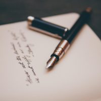 与狐说校对员南舟手持红笔在打印稿上做标记，纸张边缘贴满修订标签，工作台光线明亮